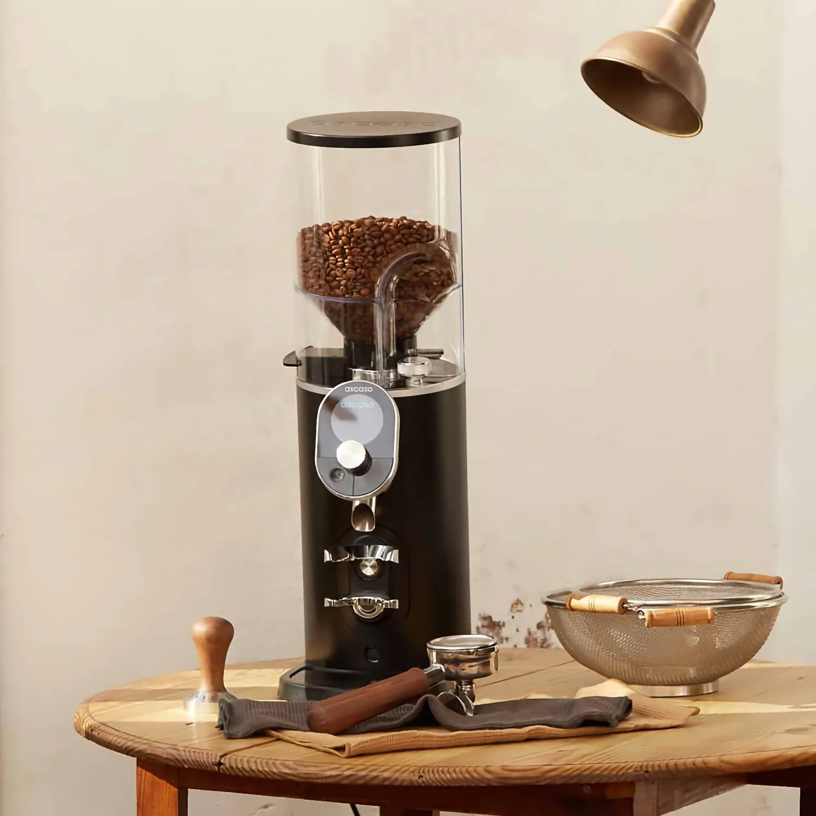 „Ascaso“ P74, its hopper filled with beans, on a wooden table beside a portafilter and tamper